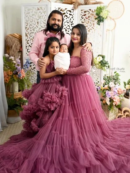 The perfect first family portrait. Mom, dad, and big sister are all coordinated in beautiful shades of pink, lovingly holding the newest member of their family. This image captures the joy and completeness that a new baby brings.