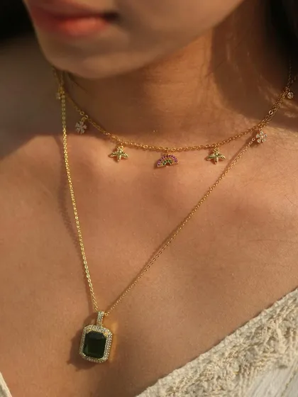 A detailed shot of our layered emerald necklace and rainbow charm choker. It's a beautiful combination of color and sparkle, perfect for elevating a simple outfit.