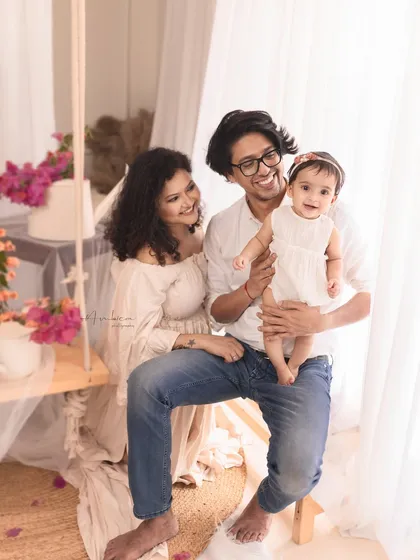 A happy family moment captured on our in-studio swing, adorned with bougainvillea for a soft, romantic feel. This is a perfect example of a modern, dreamy family portrait that feels both candid and beautifully composed.