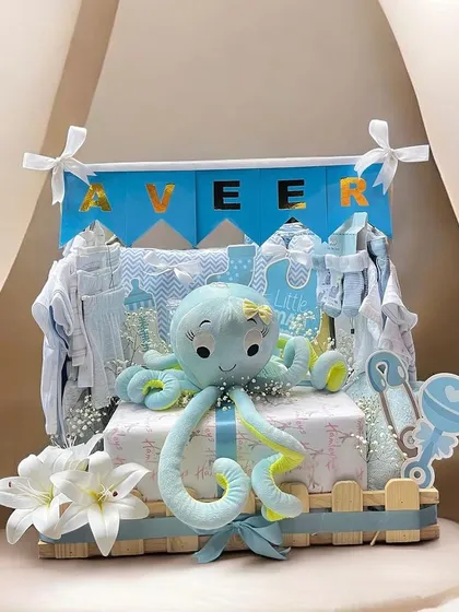 Welcome a new baby boy with this adorable and luxurious arrival hamper. It includes a plush octopus toy, a personalized 'Veer' banner, and a curated selection of baby essentials.