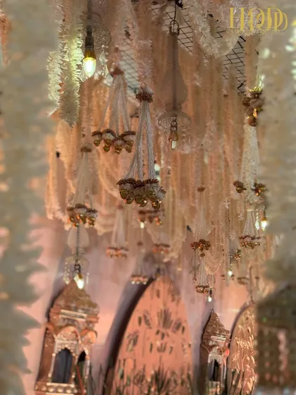 The ceiling of floral chandeliers against the warm glow of the stage, creating a rich and layered visual effect.