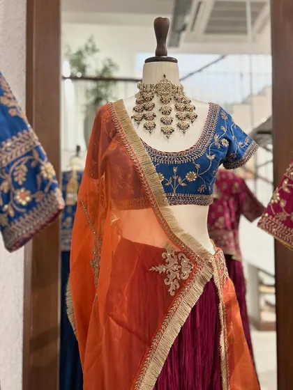 I love combining bold colors. This lehenga features a deep blue embroidered blouse paired with a magenta skirt and a contrasting orange dupatta for a vibrant, eye-catching look.