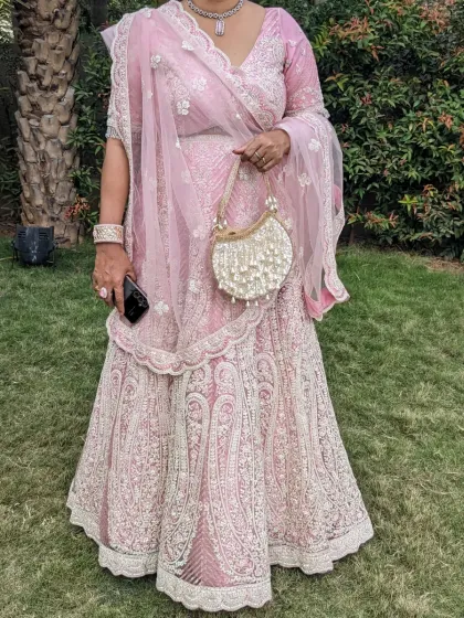 A perfect pink lehenga for a wedding party. The delicate threadwork and matching net dupatta create an elegant and sophisticated look for a wedding guest.