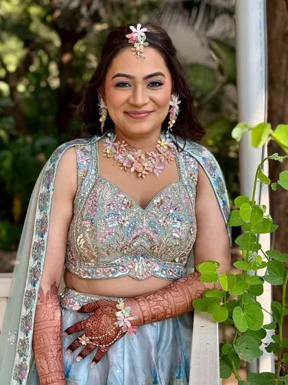 A soft, fresh, and floral Haldi look. The pastel lehenga and floral jewelry are complemented by a soft glam makeup with a pop of blue eyeliner for a modern twist.