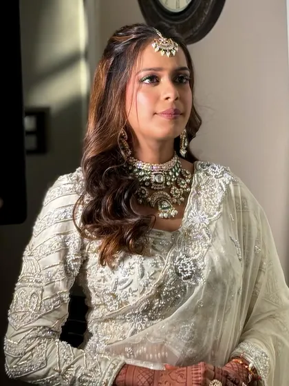 A three-quarter portrait showing the full effect of the makeup, hair, and stunning white embroidered outfit.