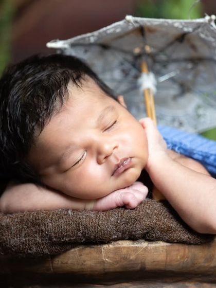 A close-up of the sleeping newborn with the umbrella, highlighting their peaceful expression.