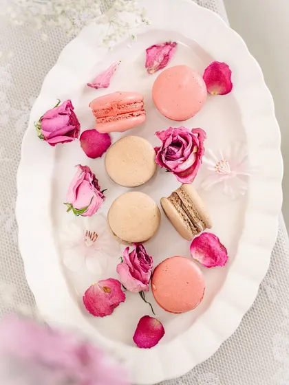 A top-down view of the macarons and roses on an elegant platter, showcasing a classic flat lay composition for baked goods.