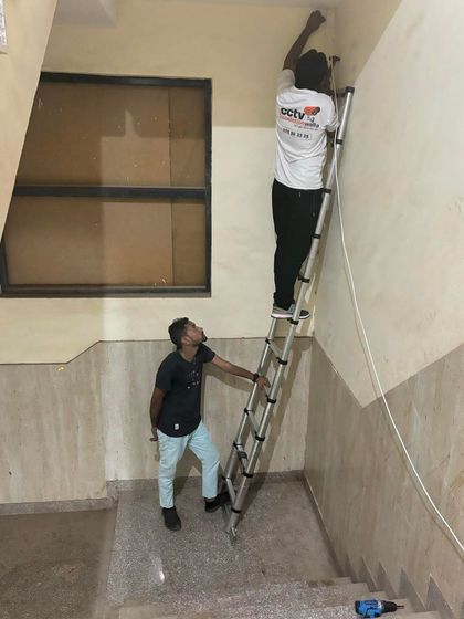 Installing a camera in a stairwell requires careful planning. My team ensures the ladder is stable and the work is done safely and correctly.
