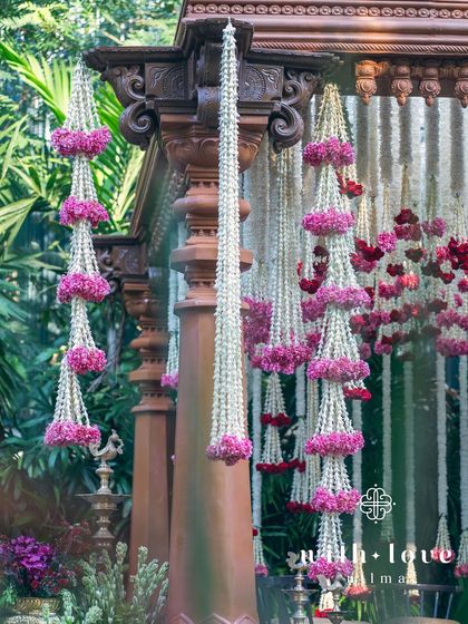 Cascading floral garlands of tuberose and pink oleander hang from the intricately carved pillars of the wedding mandap.