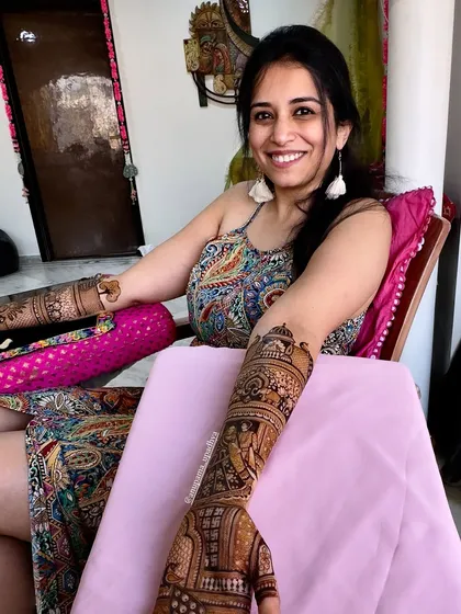 Henna hands and bridal plans. A happy bride-to-be, enjoying the process of getting her intricate mehandi done.