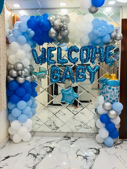 We create classic and joyful welcome home decorations for your baby boy. This setup includes a beautiful balloon arch in shades of blue, white, and silver, with "WELCOME BABY" foil letters and themed balloons like a baby bottle and star.