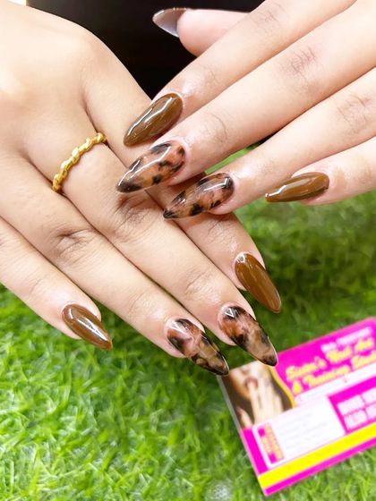 A full view of the popular tortoise shell nail art on long stiletto nails.