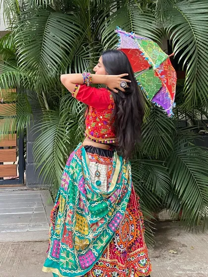 A view from the back, showing off the beautiful drape of the green patchwork dupatta and the intricate design of the lehenga.