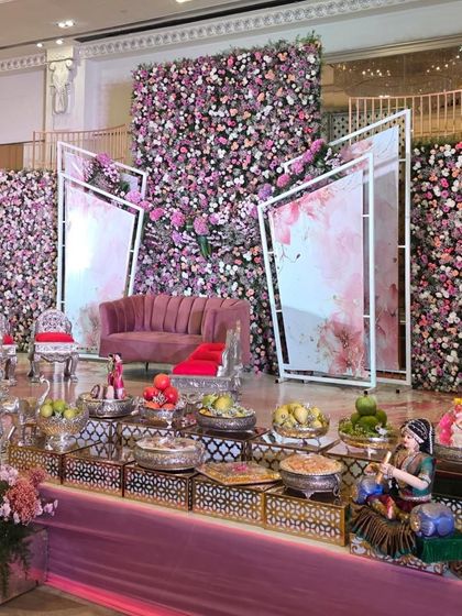 A closer view of the modern pink floral stage, showing the offering table and traditional dolls.