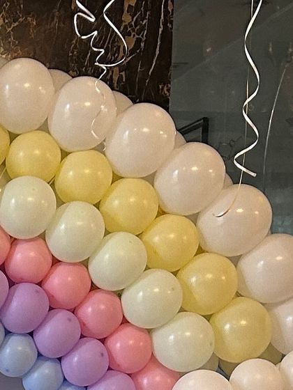 A close-up of a pastel rainbow balloon arch, showing the soft, beautiful colors blending together.