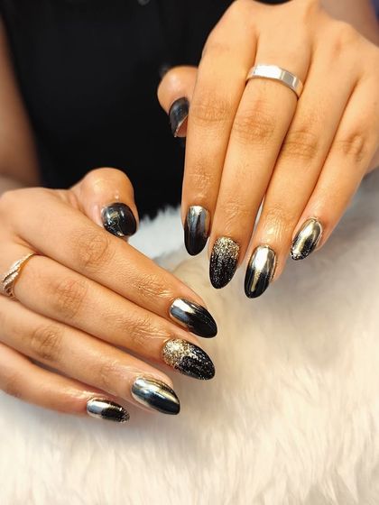 Black nails, endless possibilities. This edgy and glamorous set features a mix of black nails, gold chrome, and a sparkling black and gold glitter ombré.