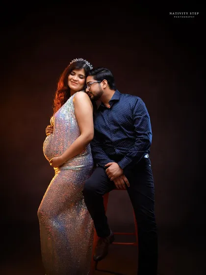 An intimate couple's portrait, with the mother-to-be glowing in a sequined gown. The pose is full of love and anticipation.