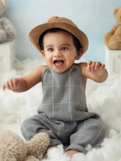 An expressive, joyful shot of a baby boy in a cloud-themed studio setup. His excitement is contagious!