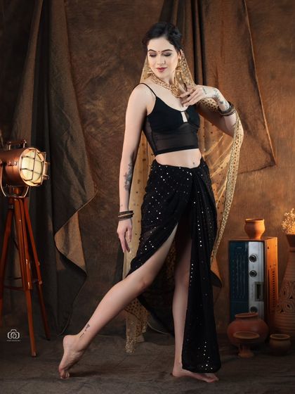 A full-length view of a modern fusion outfit, showing the high-slit skirt and contemporary top. The pose is inspired by classical dance, blending traditional and modern movements.