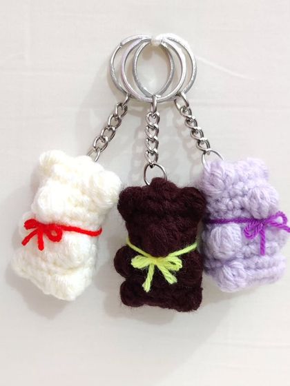 Cute and chewy-looking gummy bear keychains with little bows, available in white, brown, and lavender.