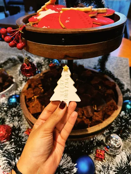 A personal touch for a Christmas event. I'm holding one of our custom-made sugar cookies, shaped like a Christmas tree. We can create custom cookies for any theme.