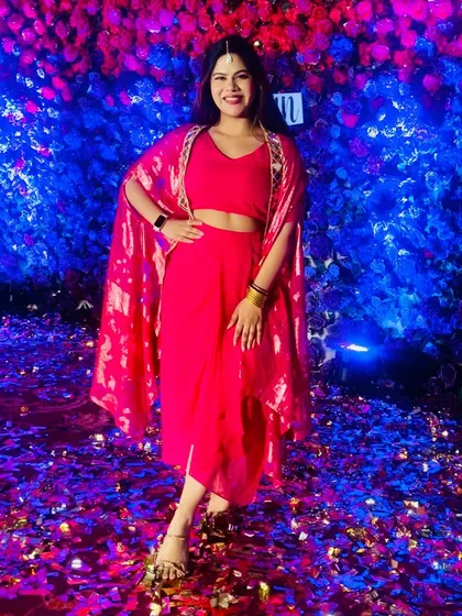 The same pink outfit against a stunning blue and purple floral wall with confetti. The colors just pop.