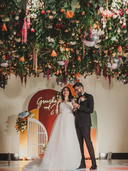The couple enjoying a champagne toast under their magnificent hanging floral installation, a perfect shot capturing the joy and beauty of their reception.