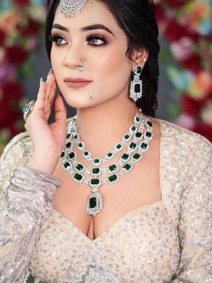 A model in a silver sequin blouse wearing a three-layered emerald and American Diamond necklace. This is a statement piece for any grand occasion.