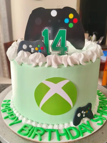 An Xbox themed cake for a gamer's 14th birthday, complete with the iconic green logo and controller toppers.