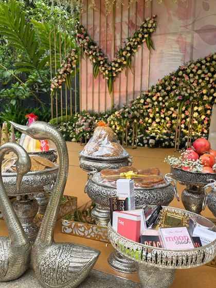 An arrangement of offerings in ornate silver bowls, featuring swan props and traditional sweets.