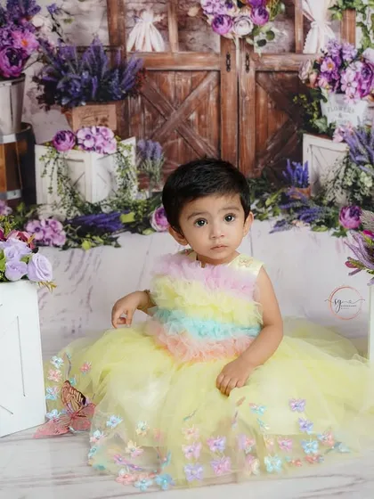A sweet, seated portrait amidst the floral props, this image showcases the intricate details of the garden theme and the baby's adorable outfit.