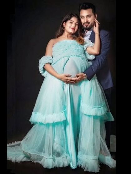 A lovely couple's portrait in the studio. The light blue ruffled gown complements the partner's suit, creating a coordinated and polished look for their maternity shoot.