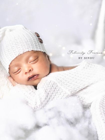 Drifting away on a soft, white cloud. This newborn portrait captures the pure serenity of a sleeping baby in a dreamy, all-white themed setup.