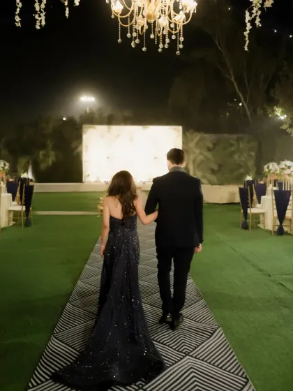 The couple walks away from the camera, hand in arm, down a beautifully lit path, a symbolic start to their journey.