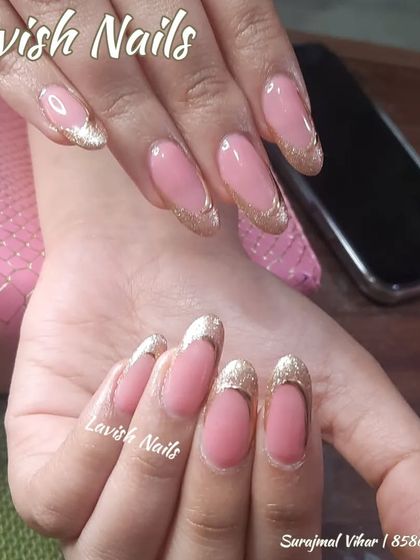 An elegant French manicure with sparkling gold glitter tips on almond-shaped nails.