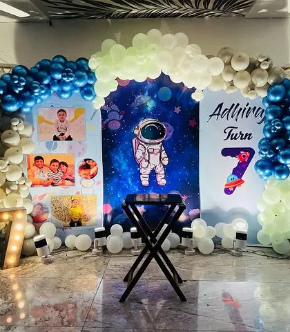 A personalized Space theme decoration, incorporating photos of the birthday boy into the backdrop along with an astronaut graphic and marquee number.