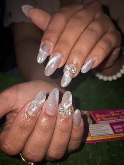 A glamorous silver cat eye set on long stiletto nails. We added 3D stone bows to the accent nails for an extra touch of sparkle and drama.