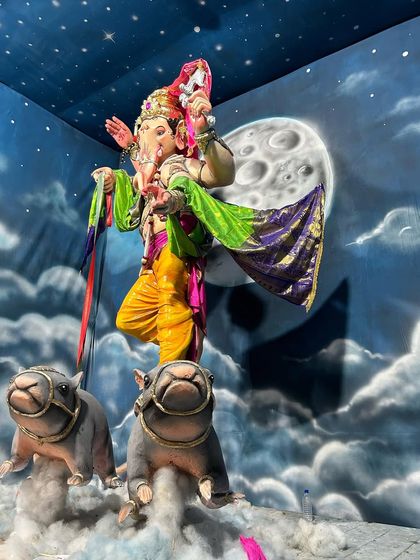 The magnificent Ganpati idol in its final setting. The painted moon and starry sky create a celestial atmosphere for the festival.