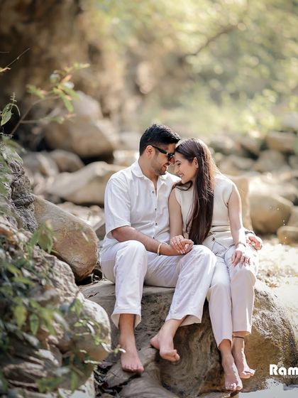 A candid moment of a couple sitting barefoot on rocks by a stream. This image captures a relaxed and authentic connection, perfect for a nature-themed pre-wedding shoot.