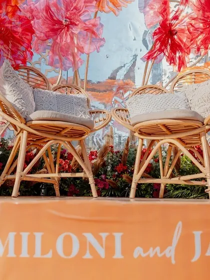 A low-angle shot of the stage, highlighting the couple's names and the beautiful rattan chairs.