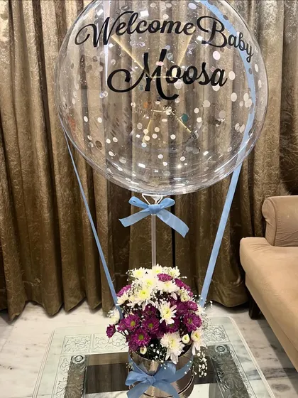 It's a boy! We customized this hot air balloon arrangement to welcome baby Moosa, using a mix of purple and white chrysanthemums and a personalized balloon with silver confetti and blue ribbons.