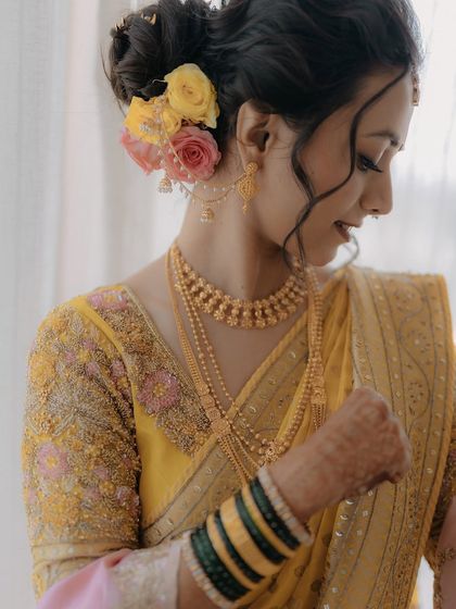 This side profile shows the beautiful floral bun and the delicate details of Krupali's Maharashtrian bridal look. The makeup is soft, letting the traditional jewelry and outfit shine.