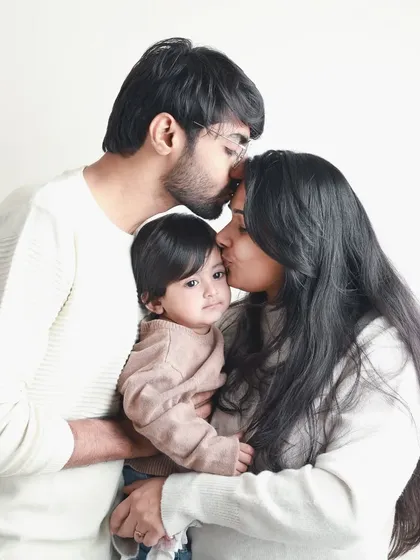 Forehead kisses and gentle embraces. This tender family portrait beautifully captures the protective and nurturing love of new parents.