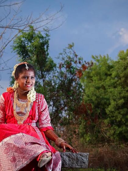 A serene portrait taken during an outdoor puberty shoot. Seated on a stone bench surrounded by nature, she looks peaceful and radiant in her traditional dress.