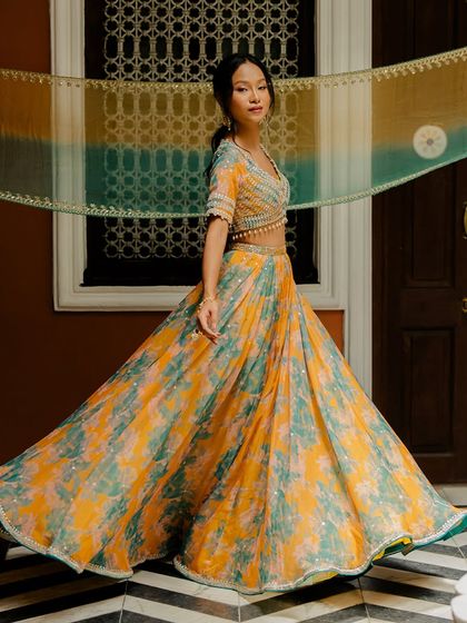 A vibrant tie-dye lehenga in shades of yellow and green, a playful and colourful choice for a mehendi or sangeet.