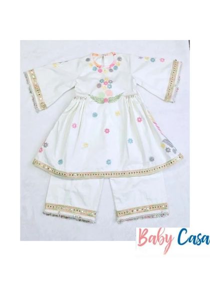 A beautiful white sharara set with multi-colored floral embroidery and mirror work. This is a perfect outfit for a little girl to wear for Diwali or a family puja.