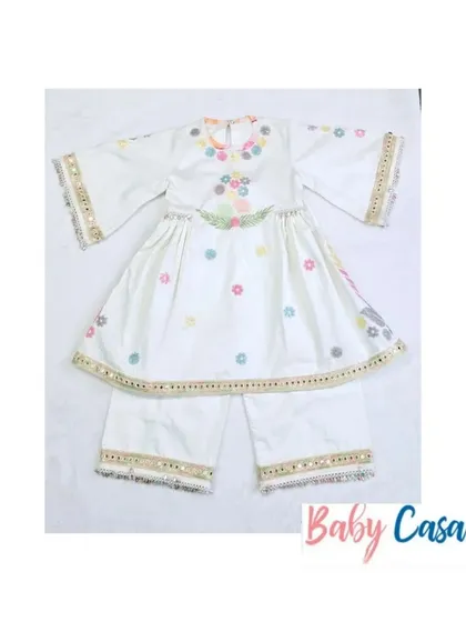 A beautiful white sharara set with multi-colored floral embroidery and mirror work. This is a perfect outfit for a little girl to wear for Diwali or a family puja.