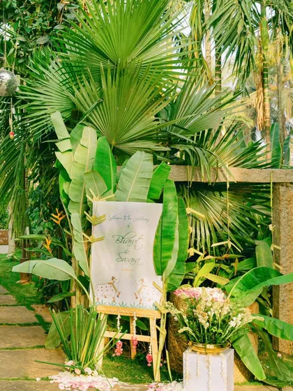 A welcome sign nestled in a lush tropical setting. We use the natural beauty of the venue to our advantage, creating pathways and entrances that feel organic and enchanting.
