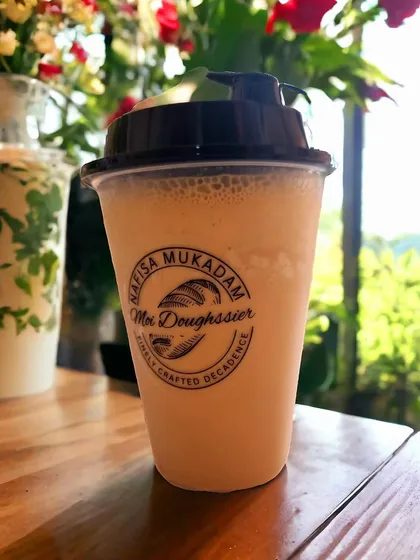 A refreshing classic cold coffee, served in a branded takeaway cup. It's a simple, creamy, and invigorating drink, perfect for a warm day.
