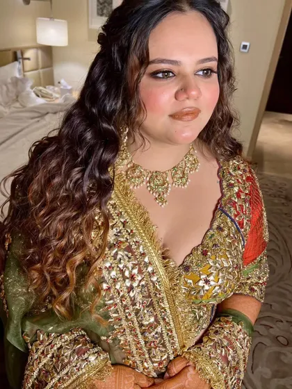 A beautiful hairstyle with natural looking curls for a mehendi or haldi ceremony. The half updo keeps the hair off her face while still looking soft and romantic.